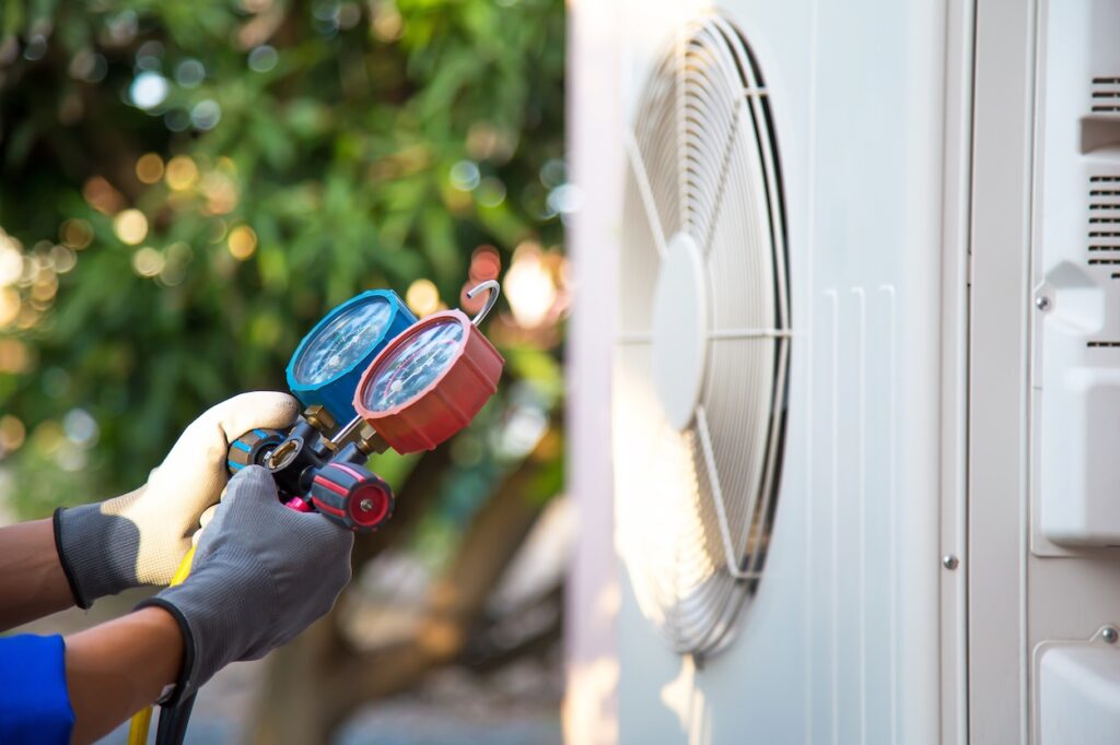Mechanic air conditioner technician using manifold gauge checking refrigerant for filling home air conditioning and air duct cleaning and maintenance