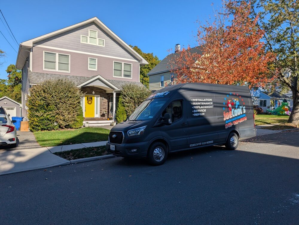HVAC service van parked in front of a suburban home on a residential street during a service visit.